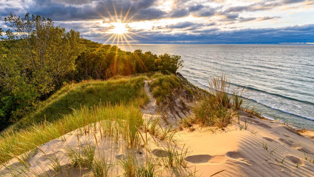From the top of Mt Baldy, the sun is seen shining behind Lake Michigan.